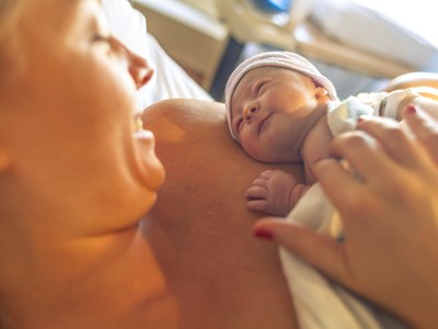 A woman with her newborn child resting on her arm. 