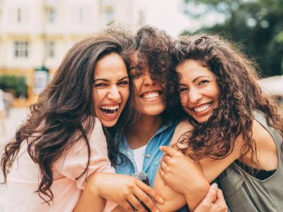 three woman hugging and smiling while looking at the camera